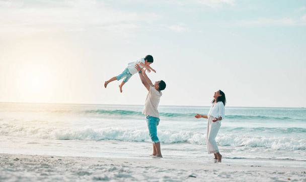 Beach, family and father lifting boy child with love, freedom and travel celebration in nature. Flying, fun and parents with kid at the ocean for bond, happy and airplane game while traveling in Bali. - Fotó, kép