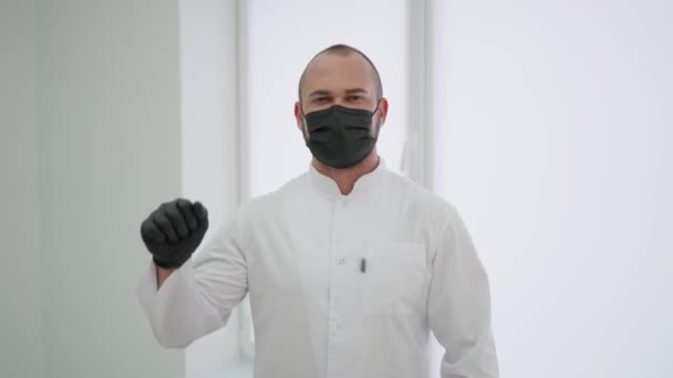 Κοντινό πλάνο ενός νεαρού γιατρού με προστατευτική μάσκα που δείχνει μια προειδοποιητική χειρονομία - Πλάνα, βίντεο