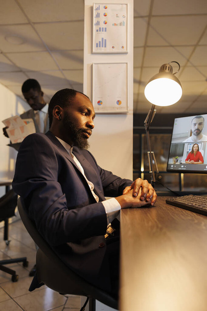 Африканський американський бізнесмен віддалено розмовляє з командою, обговорюючи маркетингову стратегію під час онлайн-відеоконференції. Різноманітні співробітники, які працюють у звіті про зростання компанії в офісі - Фото, зображення