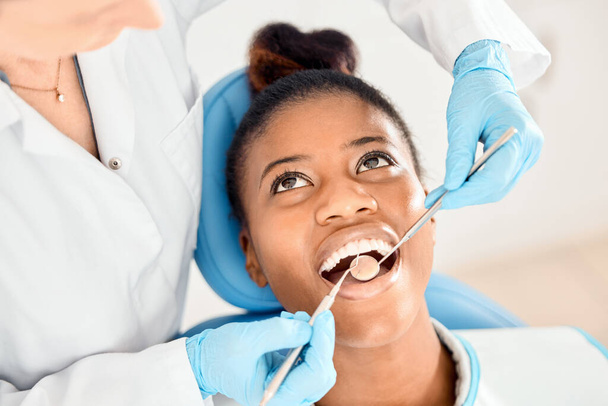 Zahnarzt, schwarze Frau und Mundreinigung von Patienten in einer Klinik mit medizinischer und medizinischer Versorgung für Zähne. Spiegel, Kieferorthopädin und Afrikanerin mit Wellness und zahnärztlichem Werkzeug mit Pflege. - Foto, Bild