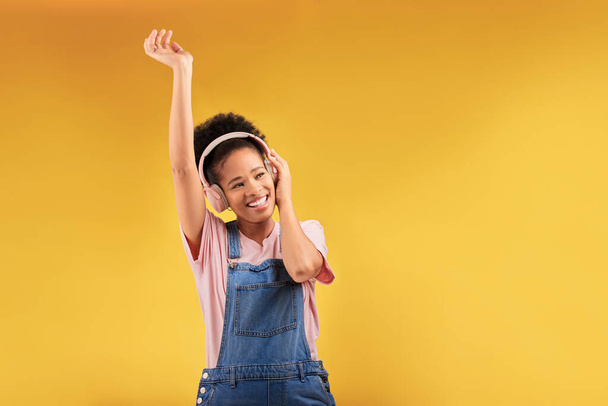 Écouteurs, musique et joyeuse femme noire dansent en studio isolé sur un fond jaune espace de maquette. Africain, souriez et écoutez de la radio, du podcast ou du son pour le jazz, le hip hop ou le streaming audio. - Photo, image