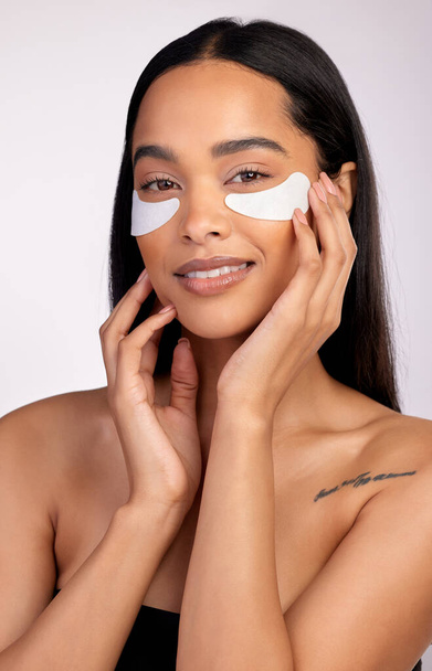 Happy woman, portrait and eye mask for skincare, collagen or dermatology against a grey studio background. Face of female person or model smiling for beauty cosmetics, patches or facial treatment. - Photo, Image