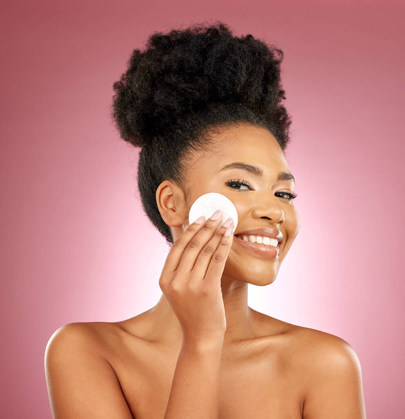 Black woman, cotton pad and skincare with makeup, portrait and facial on a studio background. Female person, face and happy model with cosmetics, aesthetic and cleaning with patches, shine and glow. - Photo, Image