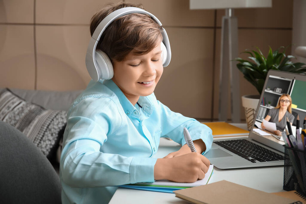 自宅で勉強しているヘッドフォンのかわいい少年. オンライン教育の概念 - 写真・画像
