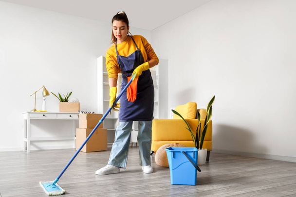 Nuori nainen moppaa lattiaa talossaan - Valokuva, kuva
