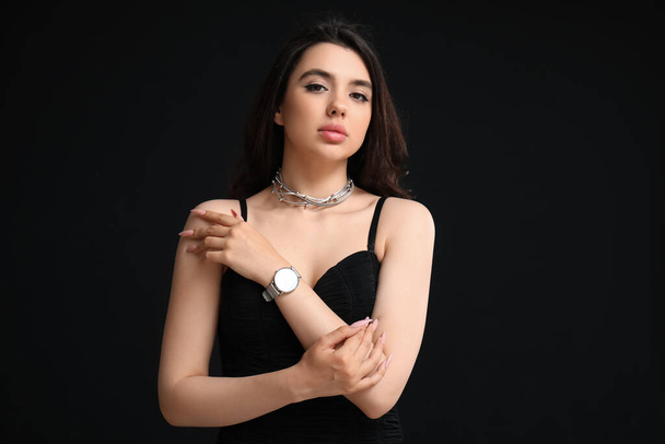 Елегантна красива молода жінка з наручним годинником на чорному тлі - Фото, зображення