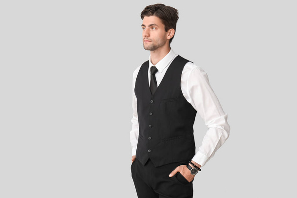 Handsome young businessman with wristwatch on grey background - Φωτογραφία, εικόνα