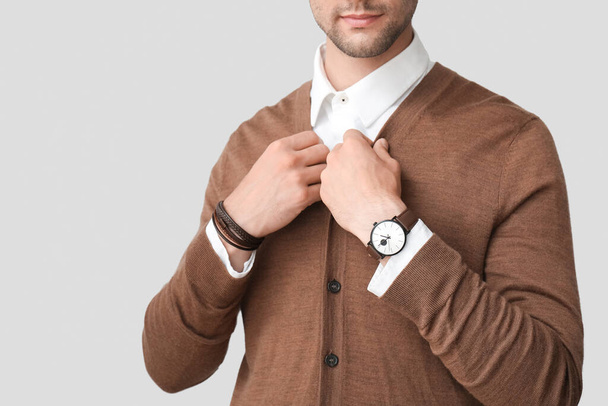 Стильний молодий чоловік з наручним годинником на сірому фоні, крупним планом - Фото, зображення