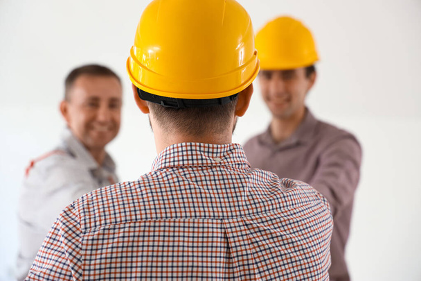Team van mannelijke bouwers aan het werk in kamer, achteraanzicht - Foto, afbeelding