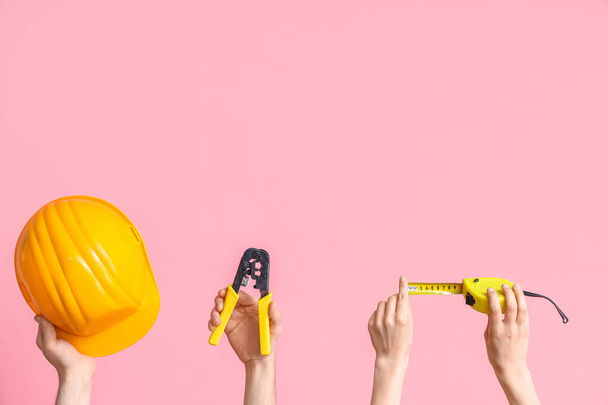 Sähköasentaja kädet työkaluja ja kypärä vaaleanpunainen tausta - Valokuva, kuva