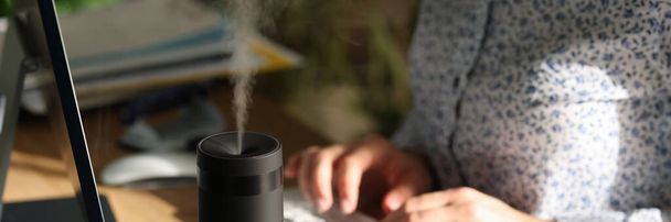 Humidifier on the desk of an office worker, close-up. Modern household appliances, ionizer - Фото, изображение