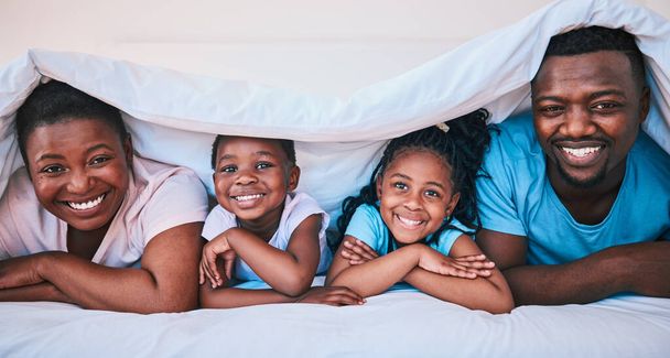 Sonrisa, familia negra y retrato en una cama con manta, relax y comodidad en el fin de semana en su casa. Feliz, cara e hijos con los padres en el dormitorio jugando, cubrir y descansar, divertido y alegre. - Foto, imagen