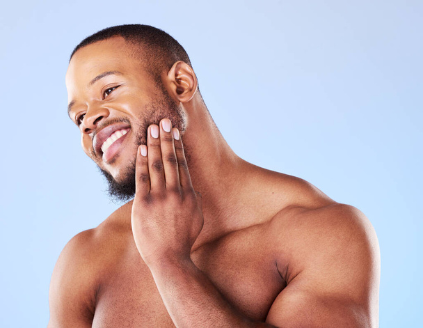 Cosmetics, cleaning and black man with skincare, muscle and grooming against a blue studio background. Male person, model and guy with treatment, shine and glow with dermatology, aesthetic and health. - Valokuva, kuva