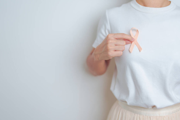 9月のUterine Cancerareness月のためにピーチリボンを保持している女性. ウタースと卵巣,子宮内膜症,解剖学,ウステリン線維症,再生医療,世界がんデーのコンセプト - 写真・画像