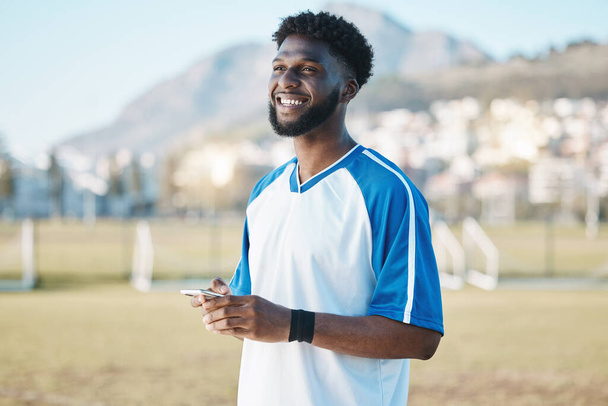 Fitness, phone or soccer player on field on social media, blog post or texting on internet or online chat. Black man, football or happy African athlete thinking of mobile app in match or sports game. - Photo, Image