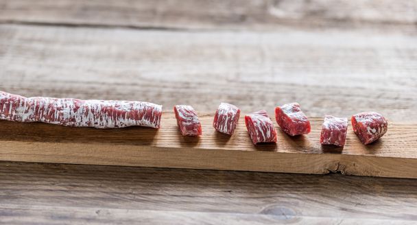 Corte o salame espanhol na tábua de madeira
 - Foto, Imagem