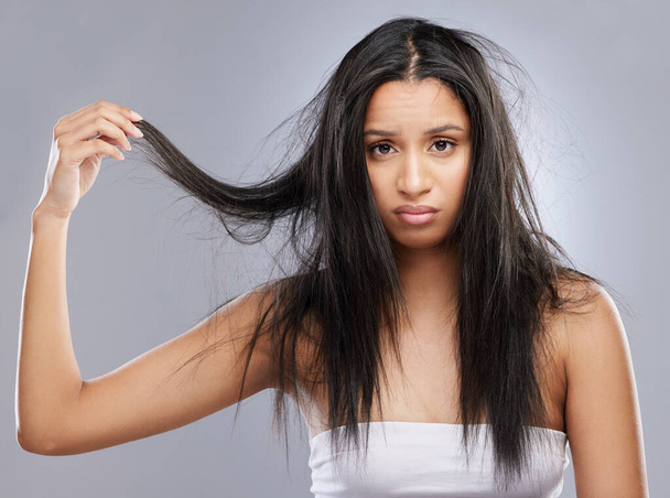 Hair, damage and portrait of woman in studio with worry for split ends, haircare crisis and weak strand. Beauty, hairdresser and face of upset female person with frizz problem on gray background. - Photo, Image