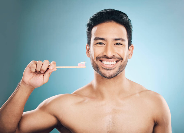 Dental, portrait and Asian man with a toothbrush, oral hygiene and wellness against a blue studio background. Face, male person and happy model teeth cleaning product, toothpaste and fresh breath. - Foto, immagini