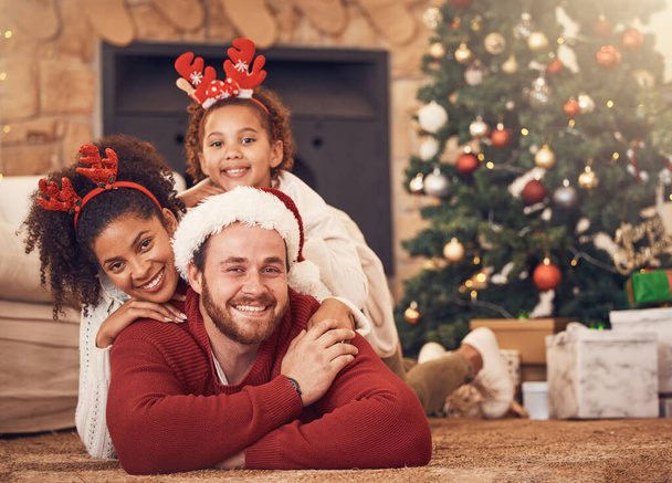 Christmas, portrait and happy family in house on floor, bonding and together. Xmas, smile and face of parents with child, interracial and African mother with father for party, celebration and holiday. - Photo, Image