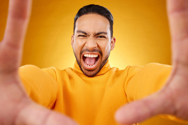 Gritando, retrato y selfie del hombre enojado en el estudio aislado sobre un fondo amarillo. Cara, gritos y persona asiática tomando foto de perfil para la memoria en la ira, frustrado o estrés en las redes sociales. - Foto, imagen
