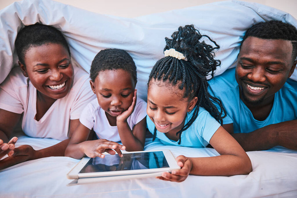 Щаслива, чорна сім'я і планшет в ліжку для мультфільму, навчання або трансляції фільму разом. Освіта, відпочинок та діти з африканськими батьками та технології для ігор, інтернету або додатку в будинку. - Фото, зображення