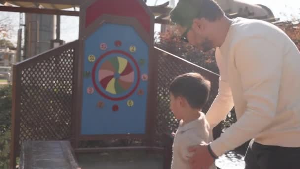 Mutlu baba küçük oğluna bir hedefe yüzük fırlatmayı öğretiyor. Yüksek kalite 4k görüntü - Video, Çekim