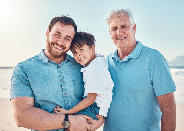 Father, grandfather and a child happy at the beach while on a family vacation, holiday or adventure. A senior man, dad and boy kid together while outdoor for summer fun, portrait and travel by sea. - Photo, Image