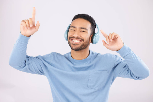 Headphones, energy and man doing a dance in a studio with music, album or playlist with technology. Happy, smile and Indian young male model dancing to song or radio isolated by a white background - Фото, зображення