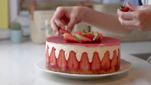 Gros plan d'une femme mains décorer un gâteau aux fraises fraîches. Images 4k de haute qualité - Séquence, vidéo