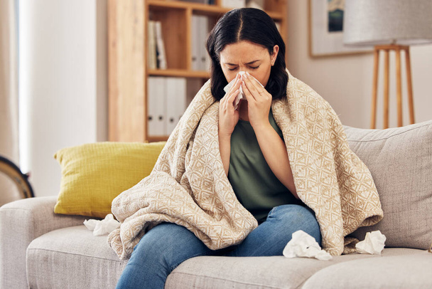 Tissue, blow nose and woman on sofa for home self care with virus, sick and healthcare or allergies. Sinus, flu and person on living room couch with allergy for medical or health and wellness risk. - Photo, Image