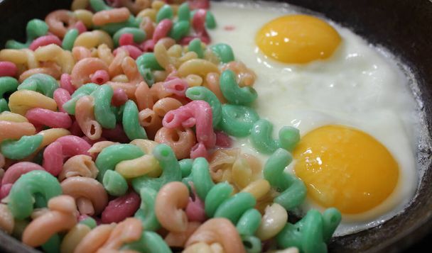 Macarrones coloreados que se calientan en una sartén con vista al ángulo de huevos fritos - Foto, Imagen