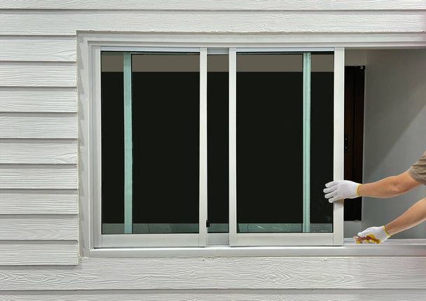 Travailleur de la construction réparant la fenêtre coulissante sur le parement en bois artificiel. - Photo, image