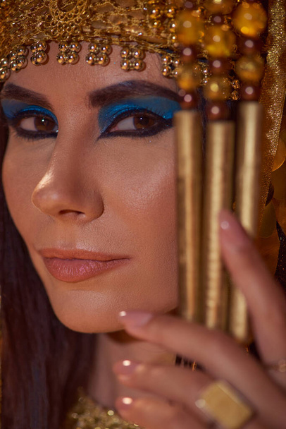 Портрет красивой женщины со смелым макияжем и традиционным египетским головным убором, смотрящей в камеру - Фото, изображение