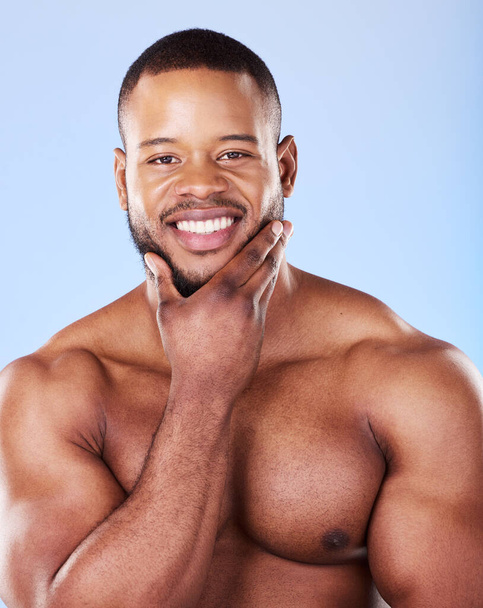 Skincare, portrait of black man with hand on face, studio and luxury skin care morning routine. Dermatology, spa cosmetics and facial beauty glow for wellness, happy model isolated on blue background. - Photo, Image