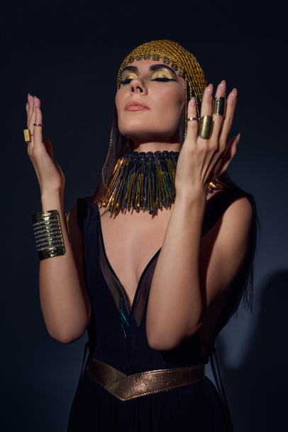 Brunette woman in traditional egyptian attire and headdress posing while standing on blue background - Foto, imagen