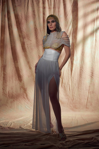 Full length of elegant brunette woman in egyptian attire posing on abstract background - Photo, Image