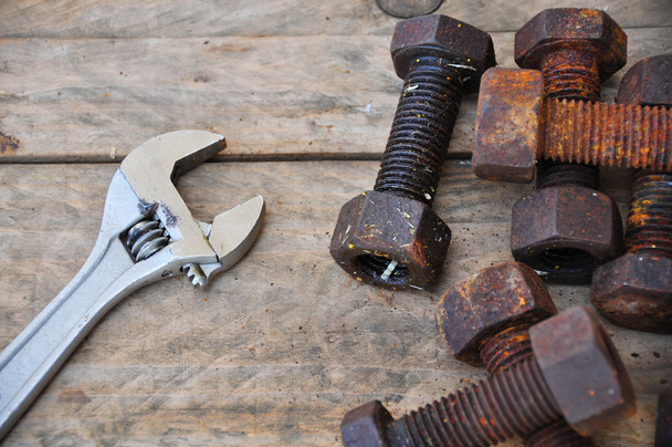 Παλαιά μπουλόνια με ρυθμιζόμενο κλειδί εργαλεία σε ξύλινα φόντο. - Φωτογραφία, εικόνα