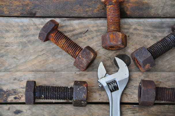 Old bolts with adjustable wrench tools on wooden background. - Photo, Image