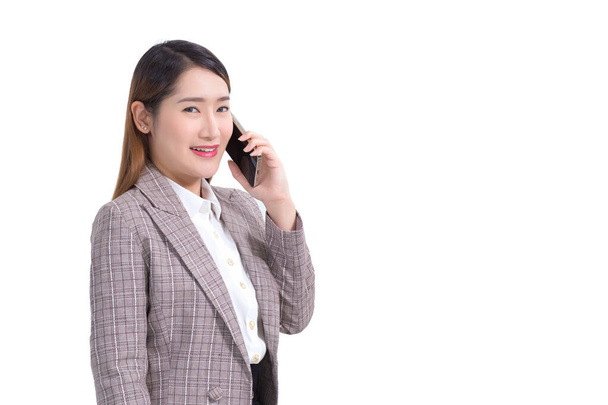 Επαγγελματική νεαρή Ασιάτισσα επιχειρηματίας σε επίσημη κοστούμι με λευκό πουκάμισο είναι χρήση smartphone για να καλέσετε τηλέφωνο για να ελέγξετε τα δεδομένα, ενώ απομονώνονται σε λευκό φόντο. - Φωτογραφία, εικόνα