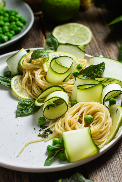 Pasta met courgette en groene erwten in een kom - Foto, afbeelding