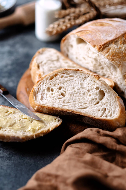 Corta el pan integral en una tabla de madera sobre una mesa con ingredientes. Comida saludable, pan de masa madre. Vista superior. Foto de alta calidad - Foto, Imagen