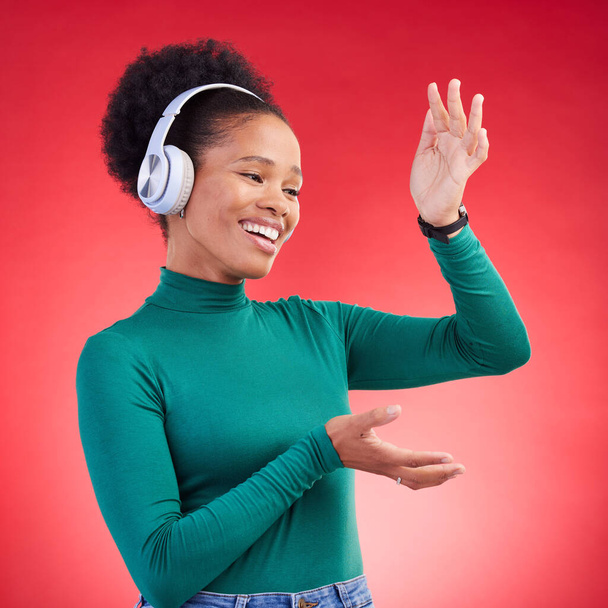Щаслива, танцювальна і чорна жінка з музичними навушниками в студії, свобода і гарний настрій на червоному тлі. Podcast, радіо та африканська жінка з трансляцією навушників, танцями та святкуванням вібрацій. - Фото, зображення