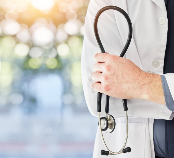 Stethoscope in hand, health and doctor with medical person, cardiology and surgeon in hospital with mockup space. Bokeh, cardiovascular healthcare and professional in clinic with expert in medicine. - Photo, Image