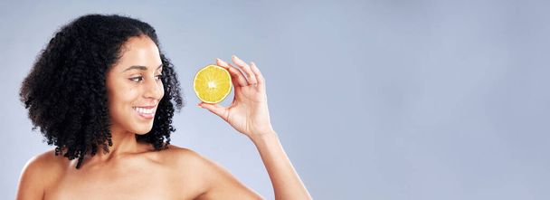 Smile, beauty and a woman with a lemon on a studio background for vitamin c and natural detox. Happy, nutrition space and a young model with fruit on a mockup banner for wellness, skincare and health. - Photo, Image