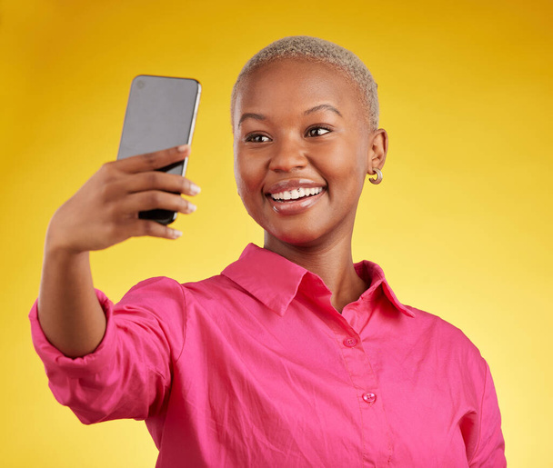 Sorria, selfie e mulher negra feliz no estúdio isolado em um fundo amarelo. Foto de perfil, fotógrafo e pessoa ou influenciador africano tirando foto para memória, mídia social ou blog na internet. - Foto, Imagem