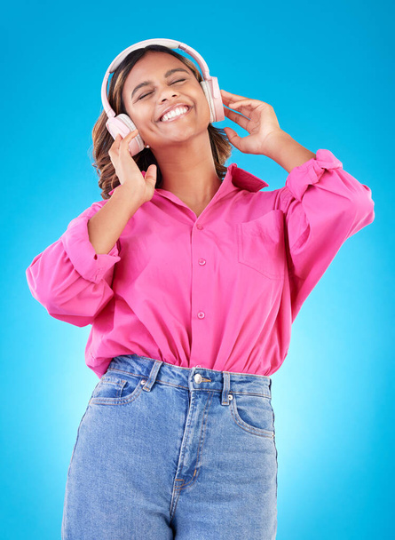 Young woman, headphones and music, audio streaming service and techno or student podcast in studio. Happy person listening to radio with gen z electronics and wellness on a blue, gradient background. - Zdjęcie, obraz