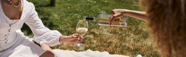 částečný pohled na africké americké přítelkyně nalévání vína na letním pikniku, banner - Fotografie, Obrázek
