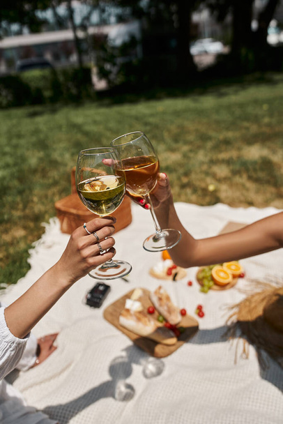 cropped view of african american women clinking wine glasses, food on blurred background, picnic - Photo, Image