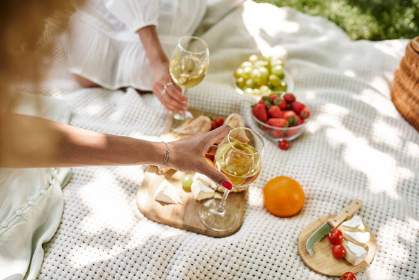 przycięty widok afrykańskich Amerykanek z kieliszkami wina w pobliżu przekąsek na letnim pikniku - Zdjęcie, obraz