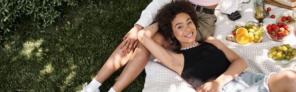 carefree african american woman lying near girlfriend in park, looking at camera, top view - Photo, Image